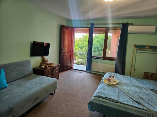 a bedroom with a bed and a couch and a tv at Regina's Guesthouse in Balchik