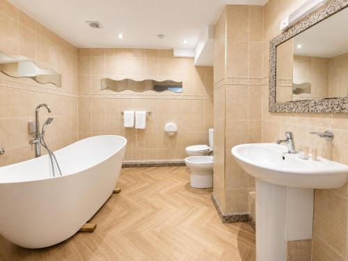 a bathroom with a tub and a sink and a toilet at Wool Merchant Hotel HALIFAX in Halifax
