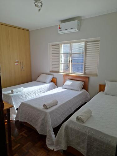 a room with three beds and two windows at Pousada Lua Nova in Sorocaba