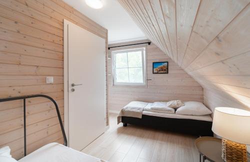 a bedroom with a bed in a room with wooden walls at Domki Nad Morzem Babki z Piasku Dziwnów in Dziwnów