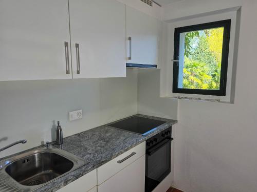a small kitchen with a sink and a window at Rustico Marietta by HolAp SA in Brissago