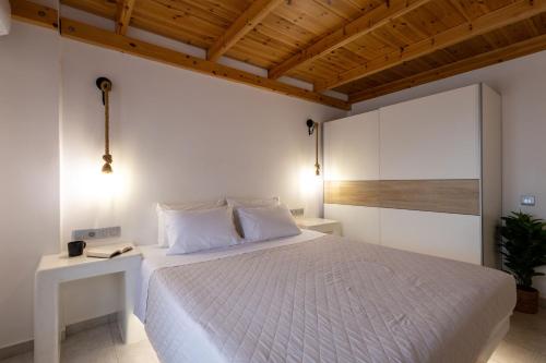 a bedroom with a white bed and a wooden ceiling at Aerial Villas in Imerovigli
