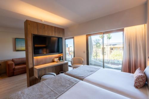 a hotel room with a bed and a flat screen tv at Turia Badajoz in Badajoz