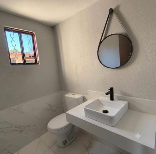 a white bathroom with a sink and a mirror at Chácara Umbelina Hospedaria in Cachoeira Paulista