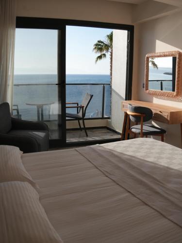 a bedroom with a bed and a view of the ocean at Ciftlique Otel Cesme in Çeşme