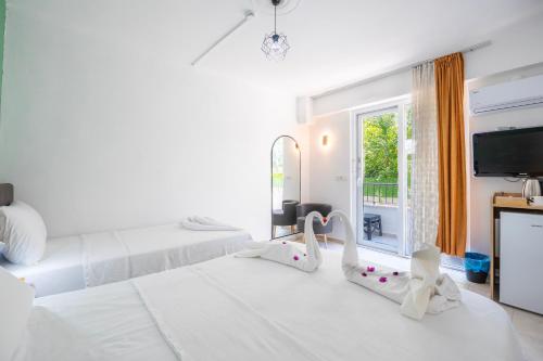 a white bedroom with two beds and a television at NEV Fethiye in Fethiye