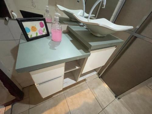 a bathroom with a counter with a sink and an umbrella at ACONCHEGO 6 - Self Check-in in Presidente Prudente
