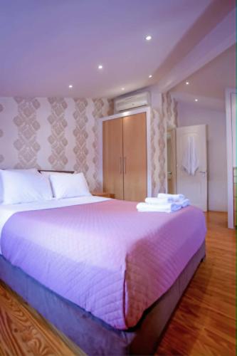 a bedroom with a large bed with a purple blanket at Guilford Loft in Corfu