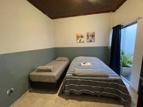 two twin beds in a room with a window at ACONCHEGO 6 - Self Check-in in Presidente Prudente