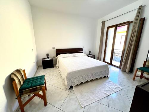 a bedroom with a bed and a chair and a window at La casa di Cleo in Gonnesa