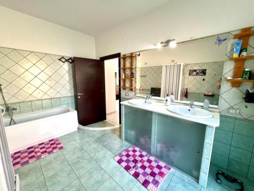 a bathroom with two sinks and a tub and a mirror at La casa di Cleo in Gonnesa