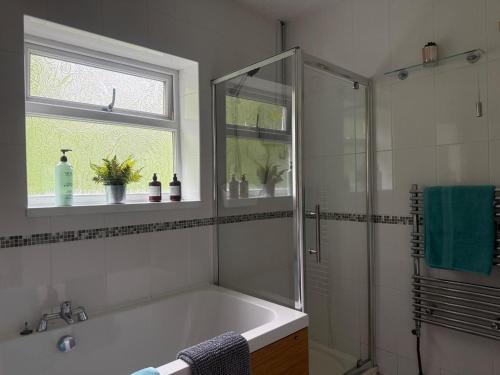 a bathroom with a shower and a bath tub at 3 Bed House - Sleeps 6 - Parking - Garden - WIfi in Pont-Nedd-Fechan
