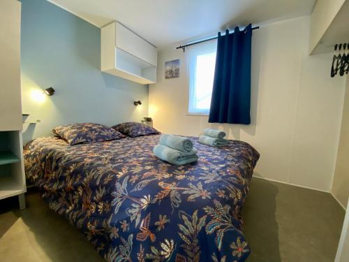 a bedroom with a bed with a blue blanket at Mobilhome camping St jacques in Sarzeau