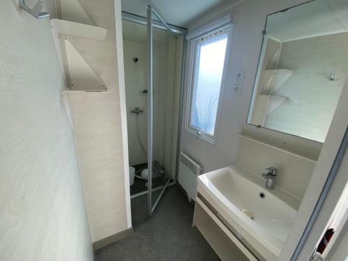 a bathroom with a sink and a shower and a mirror at Mobilhome camping St jacques in Sarzeau