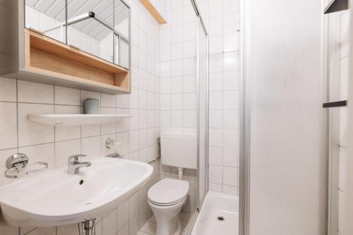 a white bathroom with a sink and a toilet at Stoderglück by Alpenidyll Apartments in Gröbming