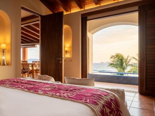 a bedroom with a bed and a view of the ocean at Residences at Las Palmas in Zihuatanejo