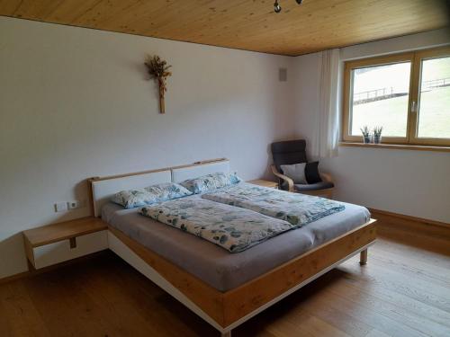 a bedroom with a bed and a chair and a window at Appartment Waldtraum in Au im Bregenzerwald