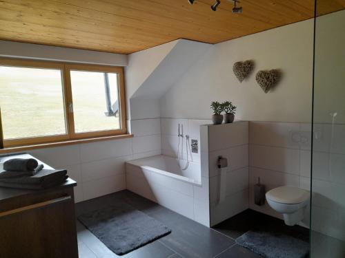 a bathroom with a tub and a toilet and a window at Appartment Waldtraum in Au im Bregenzerwald