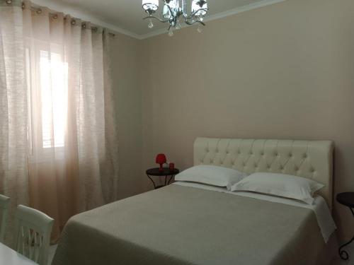 a bedroom with a large white bed with a chandelier at Andrea House in Berat
