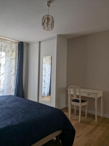 a bedroom with a bed and a desk and a chair at Gîte LM in Bourbonne-les-Bains