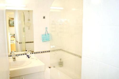 a white bathroom with a sink and a tub at La croisière in Capbreton