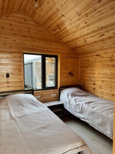 two beds in a wooden room with a window at Tosor Barnhouse in Tossor