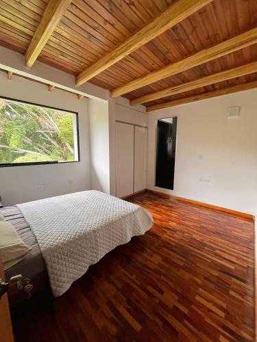a bedroom with a bed and a large window at Refugio de Guacamayas in Mérida