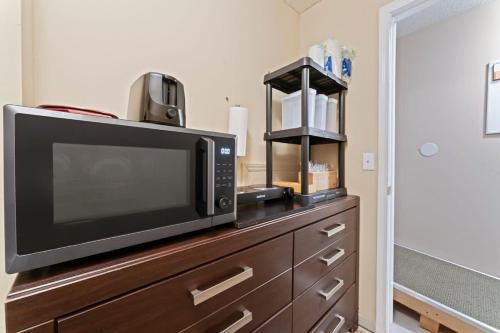 a microwave sitting on top of a wooden dresser at Mid-Century Studio Kitchenette Wi-Fi in Jacksonville