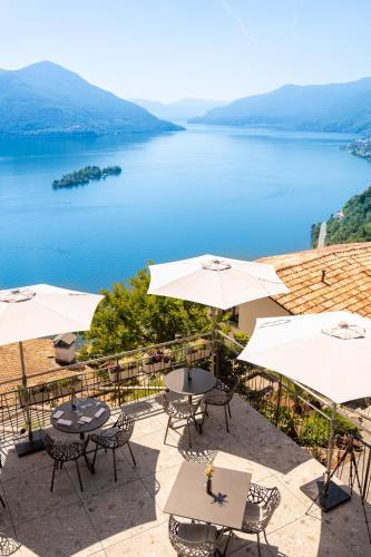 a patio with tables and umbrellas and a lake at Exclusive Boutique Hotel Elisabetta in Ronco sopra Ascona