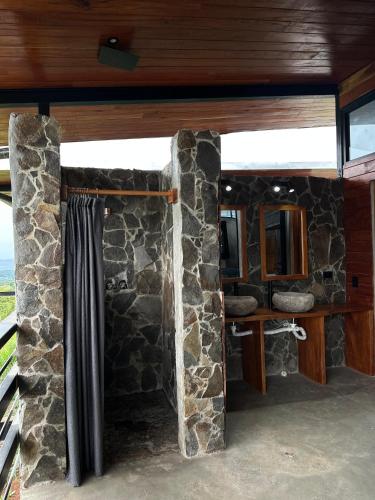 a bathroom with a stone wall and a mirror at Finca Mirador De Gualaca in Gualaca