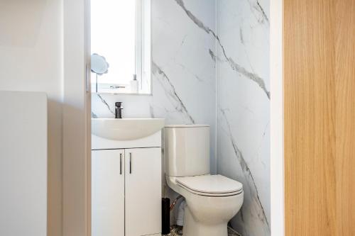 a white bathroom with a toilet and a sink at The Hide at St Andrews in Fife