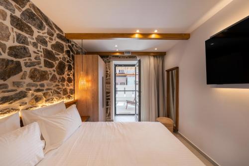 a bedroom with a bed with a stone wall at Mylopetra Suites Sarti in Sarti
