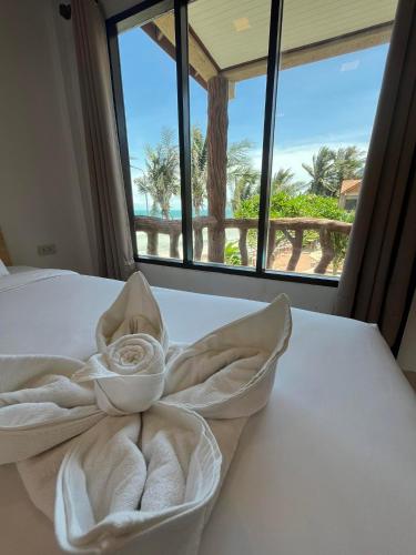 a bed with a towel on it in front of a window at SWIMS! a Social Beach Resort in Haad Rin