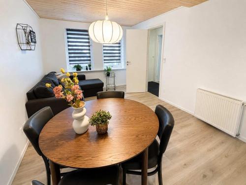a dining room table with chairs and a vase with flowers at Klaksvik Mountain View Stay in Klaksvík