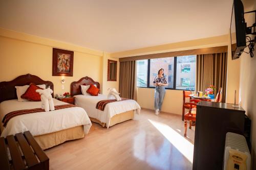 a woman standing in a hotel room with two beds at Hotel Agustos Cusco in Cusco