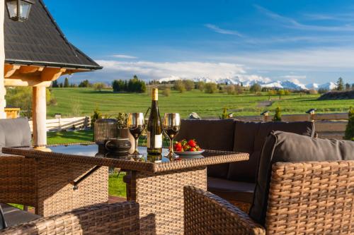 a patio with a table with wine bottles and glasses at Sękata Chata góralski domek z kominkiem in Szaflary