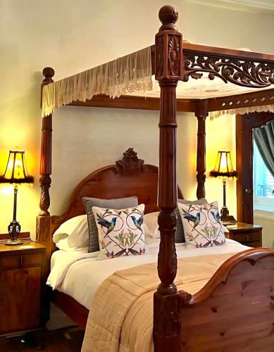 a bedroom with a wooden canopy bed with pillows at Chateau Mas Levrault in Saint-Priest-Taurion