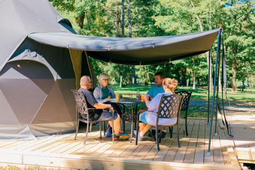 a group of people sitting at a table under a tent at Luxury Catskill Mountains Dome Retreat in Gilboa