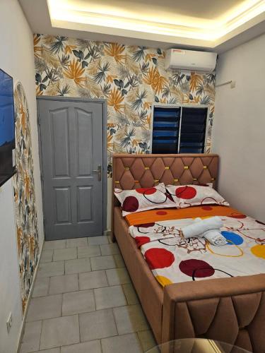a bedroom with a bed and a wall with flowers at 1e Studio Moderne au cœur de Cocody 7e tranche- Tout inclus in Cocody