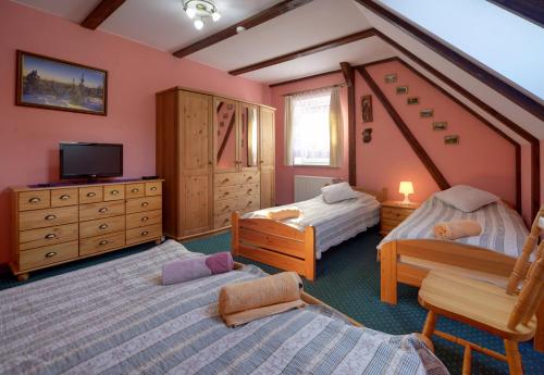 a bedroom with two beds and a tv in it at Sobiesz - Pokoje Gościnne in Jagniątków