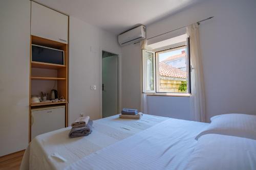 a bedroom with a large white bed with a window at Lumina Apartments in Korčula