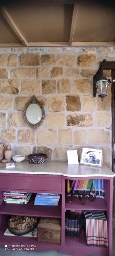 a stone wall with a table and a shelf with books at Il Borghetto Country Charme in Cefalù