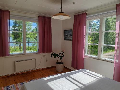 a bedroom with red curtains and a potted plant at Hirsipirtti in Inari