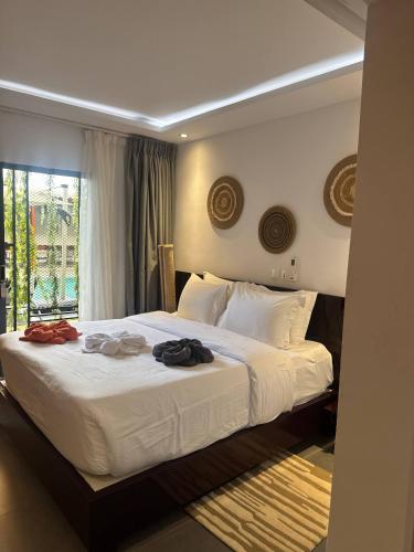 a bedroom with a large white bed with clothes on it at Family House Assinie in Assinie