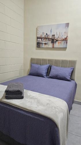 a bed with purple sheets and a painting on the wall at Kitnet Completa em Cotia com Garagem 04 in Cotia