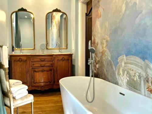 a bathroom with a tub and a painting on the wall at Chateau Mas Levrault in Saint-Priest-Taurion