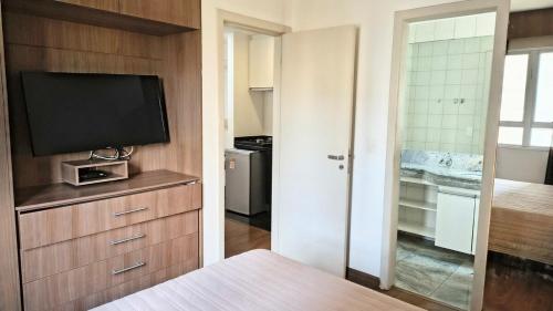 a room with a television and a kitchen with at Flat Niagara Belo Horizonte in Belo Horizonte
