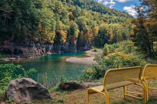 a yellow chair sitting in front of a river at Cozy Mountain Dome Escape in the Catskills in Gilboa