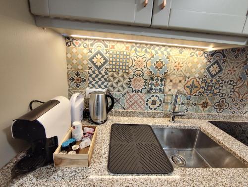 a kitchen counter with a sink and a tile wall at Abrigo da Serra - Soajo Mountain Lodge in Adrão
