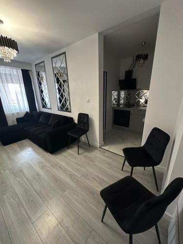 a living room with a black couch and chairs at Imperial Apartament in Gniezno